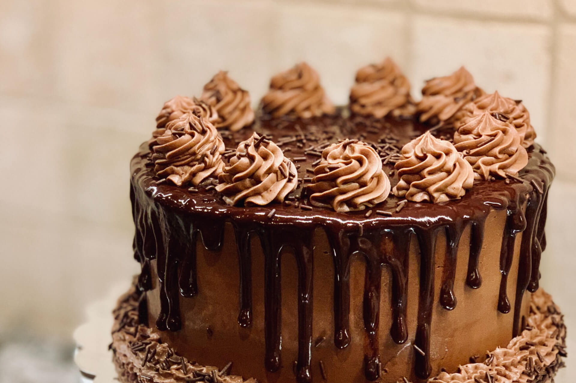 Chocolate drip cake with piped cream rosettes